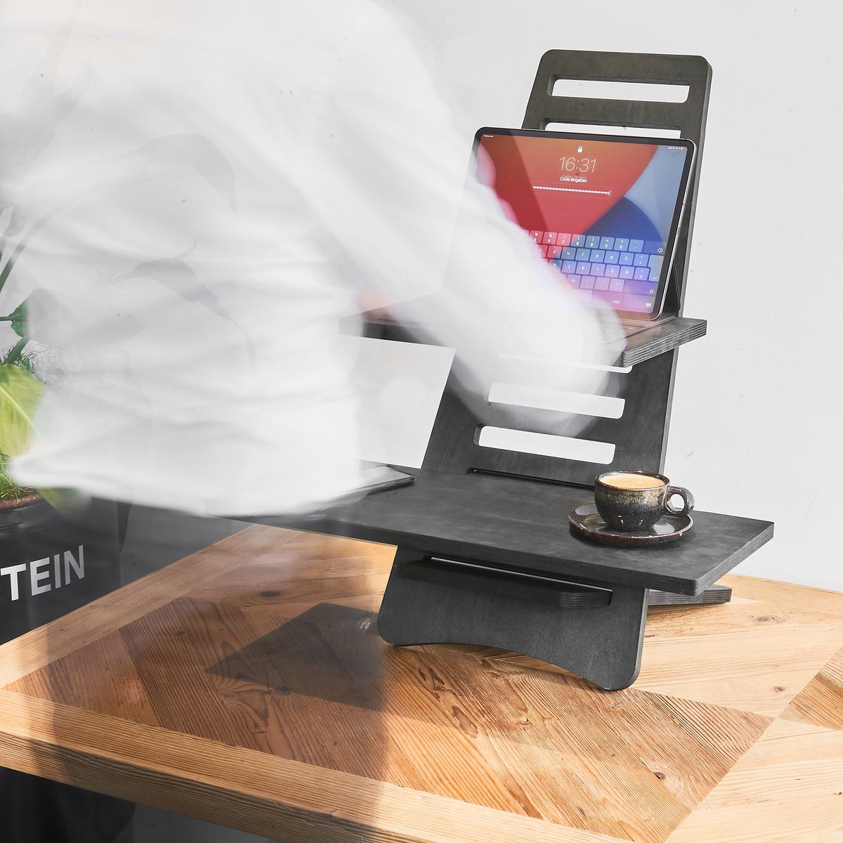 Ein Mann, der an einem auf einem Schreibtisch aufgebauten Stehtisch mit seinem Tablet arbeitet