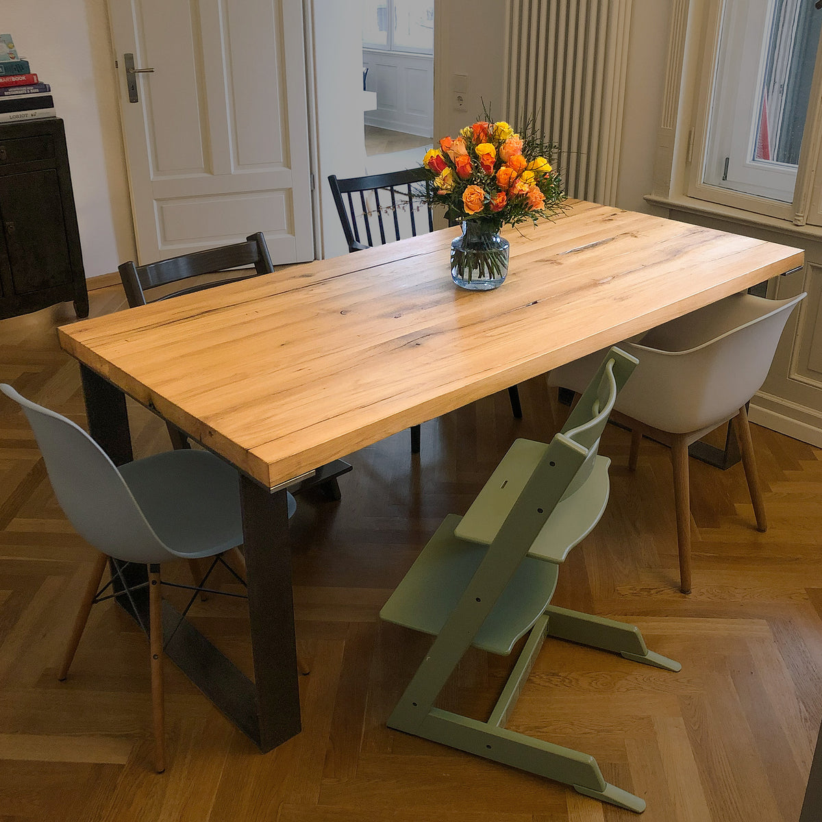 Tisch aus Altholz Eiche und zwei Rohstahlframes im Raum mit vier unterschiedlichen Stühlen