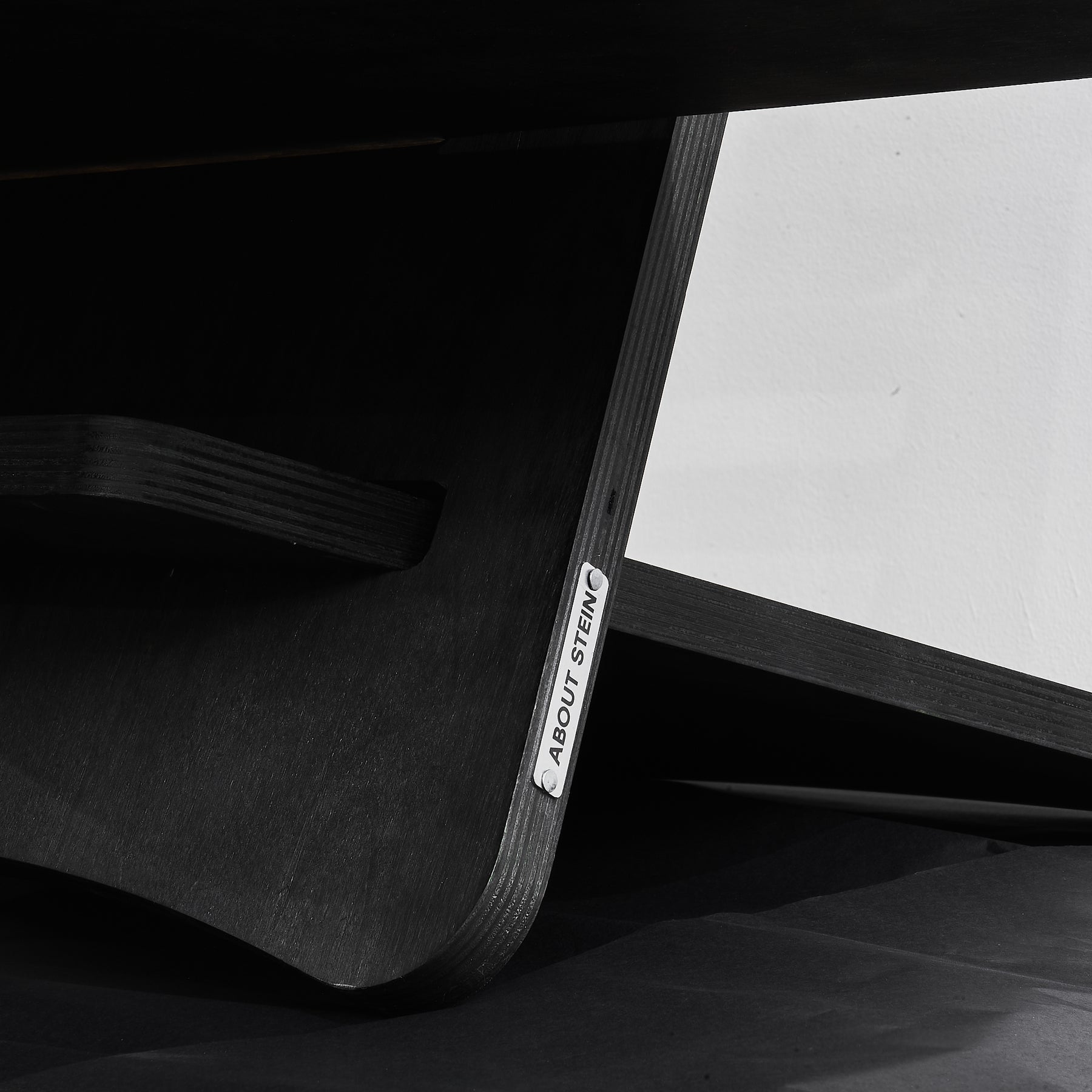 Detailansicht schwarzer Stehtisch aus Holz. Mit metallischem Logo von About Stein.