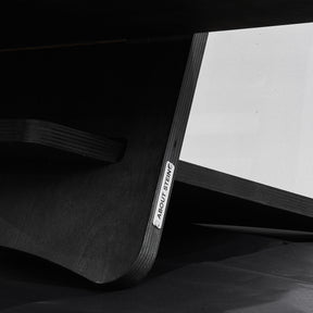 Detailansicht schwarzer Stehtisch aus Holz. Mit metallischem Logo von About Stein.